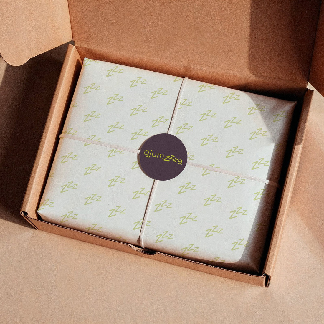 Gjumza gift box wrapped in Zzz pattern tissue paper with a round logo sticker
