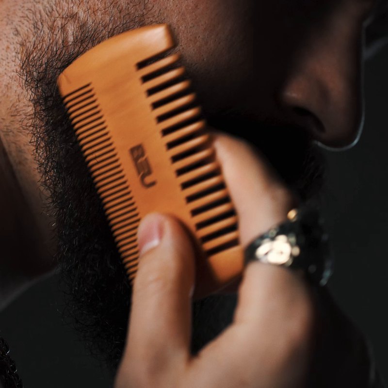 Bearded man grooming with a BEU wooden beard comb
