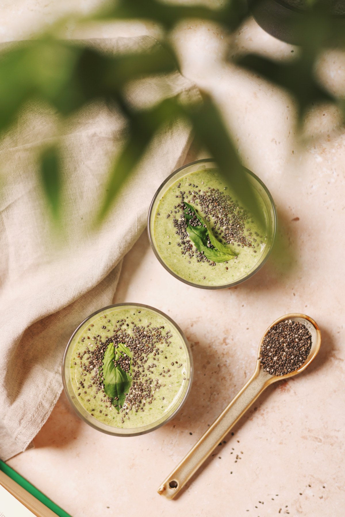 Two green smoothies topped with chia seeds and basil