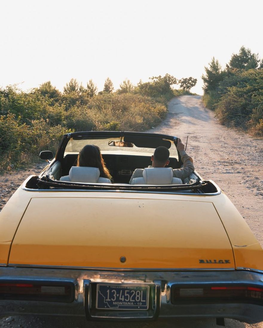 Couple driving the yellow convertible up a dirt road