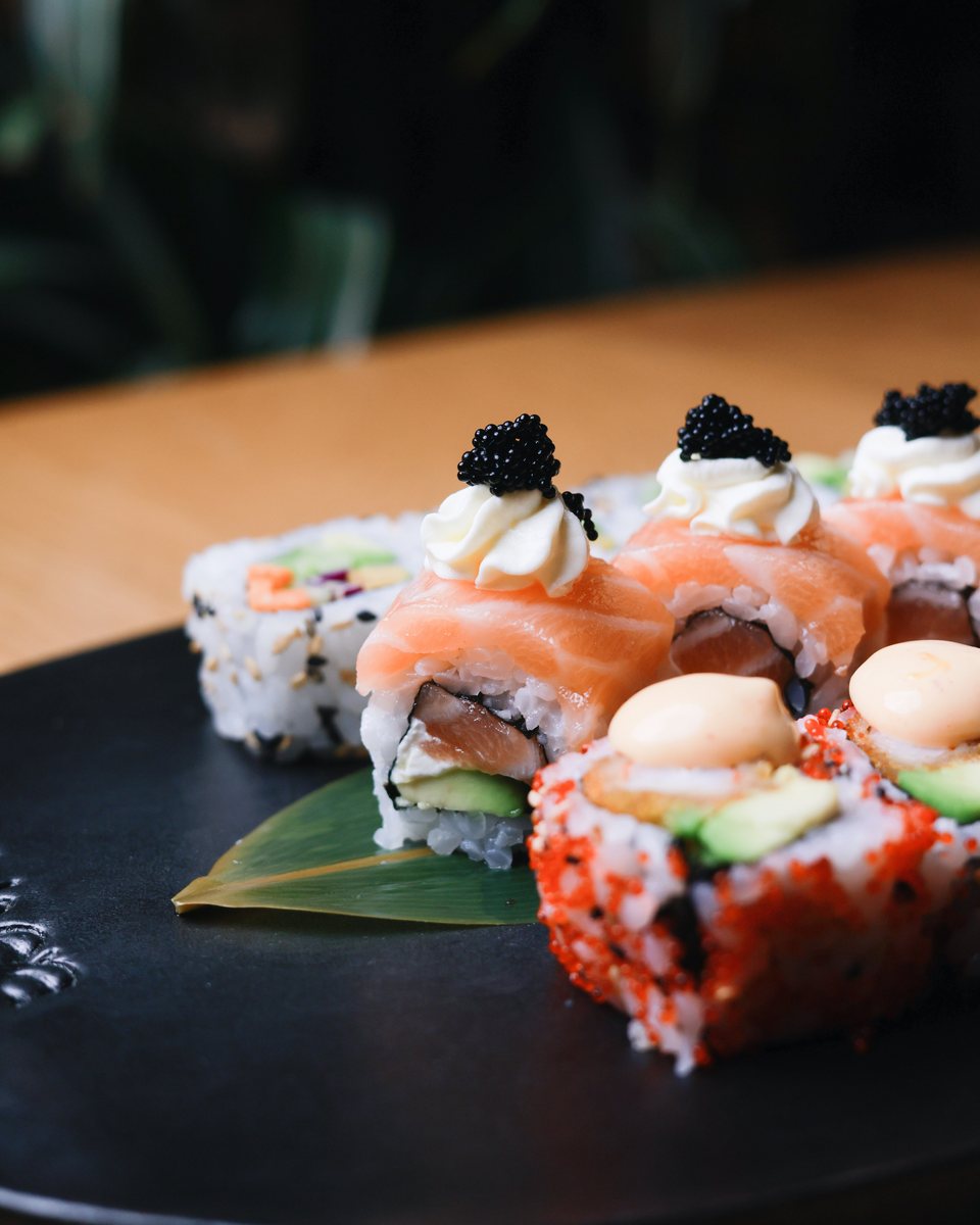Salmon and tobiko sushi rolls on a black plate